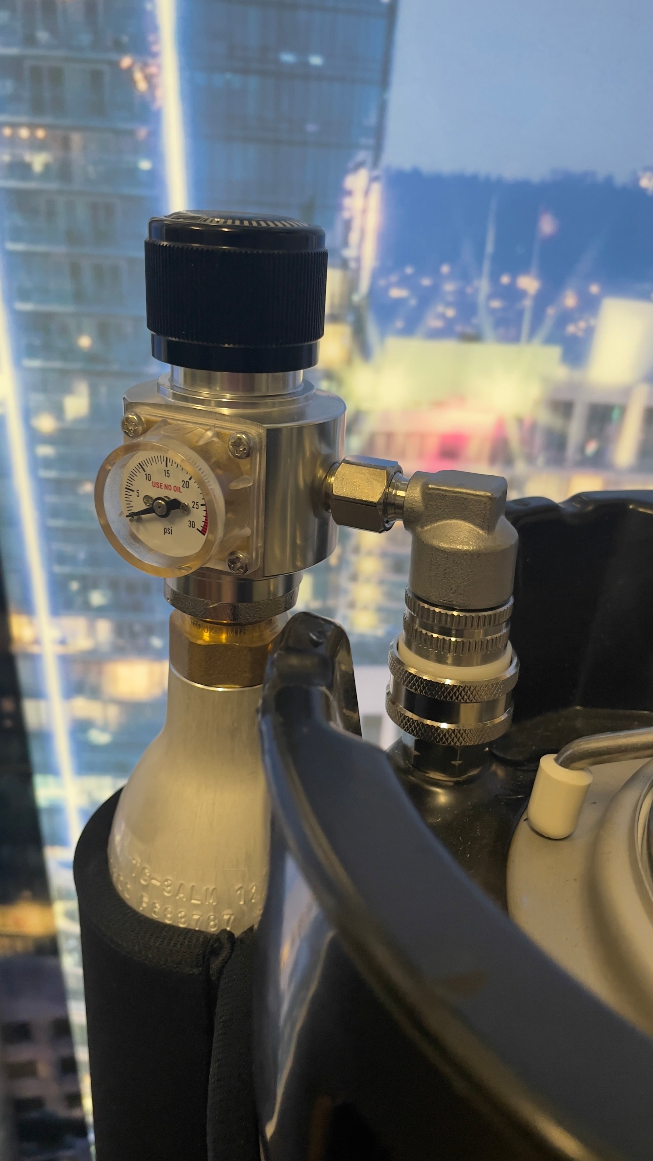 A regulator assembly with a pressure gauge, stainless steel quick connect ball lock, and rotating dial for pressure adjustment, intended for use with 500g co2 cylinders on 10L Big G Gloria Keg shown attached to 10L Big G Gloria Keg