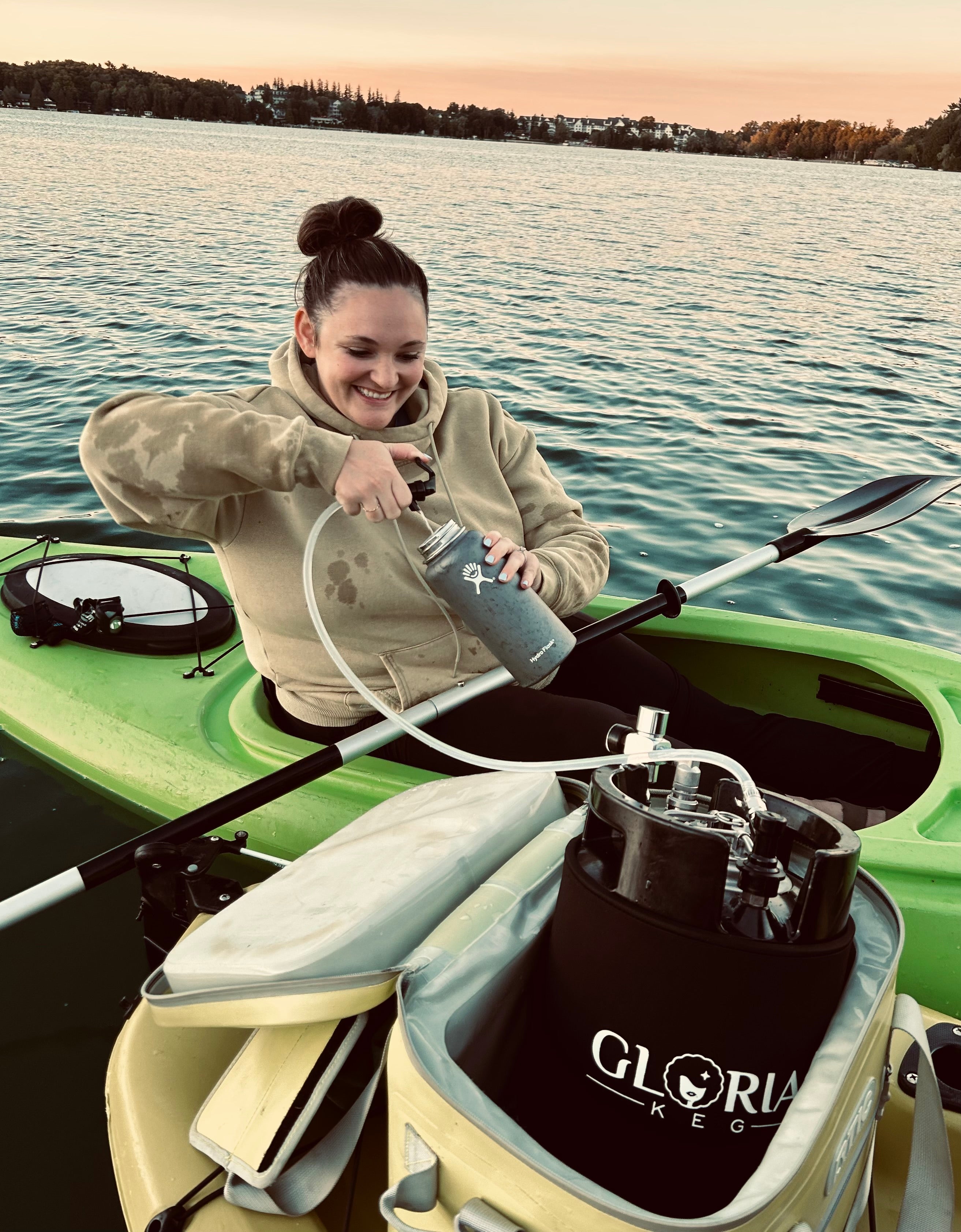 Black 7L Gloria Keg being used on a kayak on a lake with picnic tap assembly