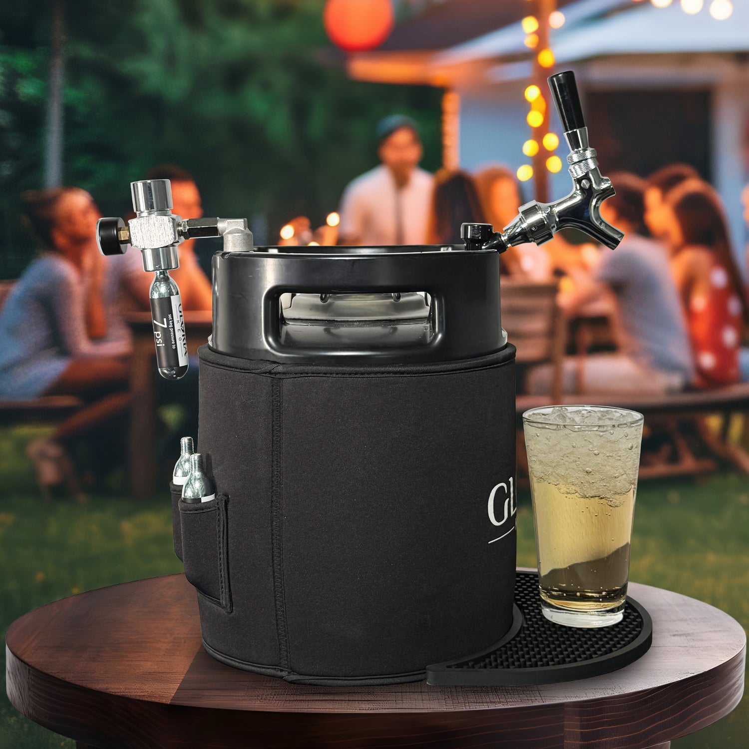 Black 7L Gloria Keg with a poured iced beverage on a table outdoors with people socializing and having a great time in the background